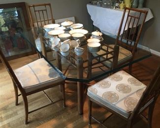 Rattan style table with glass top and four upholstered chairs.