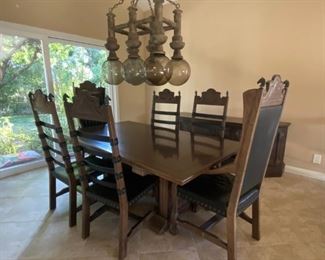Dining room table. End chairs have arms and full backs. Side chairs are open leather slats. All chairs have unique horse heads as decor.