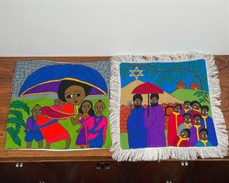 (2pc) EMBROIDERED PILLOWCASES | including a family under an umbrella "made in Ethiopia by Nacoej", and a pillow with villagers before a star signed "Askenew Ayale"; both 16 x 16 in. 