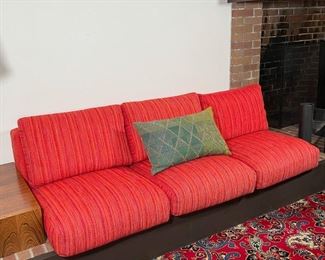 CUSTOM DESIGN SEATING CUSHIONS | orange pattern wool fabric; having a bolstered backrest, three seating cushions, three back cushions; h. 17 x 75 x 37 in.; cushions only, they are elevated on a built-in platform 