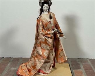JAPANESE DOLL / MODEL | showing a standing geisha with fan in an orange robe; h. 19 in. 