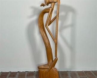 CARVED NATIVE AMERICAN MUSICIAN | finely carved from figured wood, the sinuous figure plays a flute like instrument; h; 24 in. 