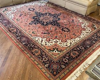 GEOMETRIC SCULPTED CARPET | having a central medallion with red ground, beige highlights, and a dark blue border; great fringe; 12-ft-3in x 9ft-1in.