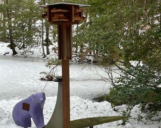 MODERN STONE SCULPTURE BENCH | Designed as a contemporary square birdhouse on a post supporting a demi-lune form stone bench, one side decorated with a painted formed purple bear with a steel drawer; h. 100 x 60 x 60 in.