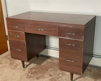 MID CENTURY DIMINUTIVE DESK | Laminated top, central drawer flanked by two banks of two drawers; h. 29 x 40 x 20 in.
