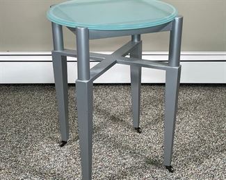 CONTEMPORARY SIDE TABLE | glass top on a silver painted wooden frame with casters; h. 22 x dia. 19 in.