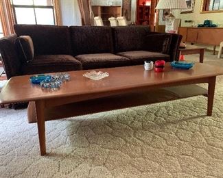 BID ITEMS: Danish Modern Teak "Surfboard style" coffee table damage to lower tier shelf where it connects to leg (does not affect functionality)  Measures 69" Long, 23" at greatest width and 16" Height 