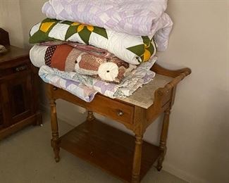 Small washstand and assorted quilts