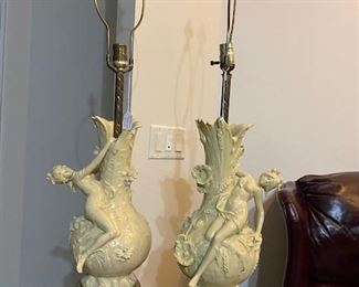 A pair of signed figural Auguste Moreau table lamps, possibly bronze. Louis Auguste Moreau, was a French sculptor best known for his bronze-cast figurines. His Art Nouveau works often depicted women, children, cherubs, and historical figures adorned with floral motifs and ornaments. Born in Dijon, France in 1855 to a celebrated family of sculptors, including his father, Auguste Moreau, he went on to regularly exhibit his work at the Paris Salon from 1861 on. The artist died in 1919 in France. (From ArtNet.com)