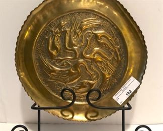 round brass repousse tray with black metal hanger