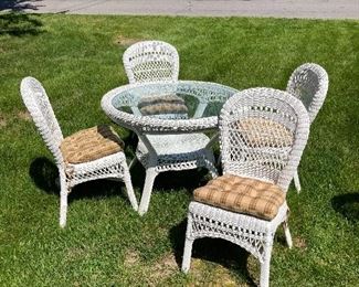 Round wicker table with glass top and four matching chairs in excellent condition