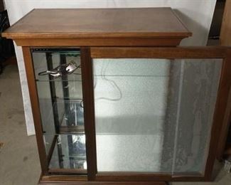 Lighted wood & glass display case with sliding door and mirror backdrop