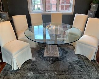 Clean glass top table with six beautiful skirted parsons dining chairs in ivory. Accent rug