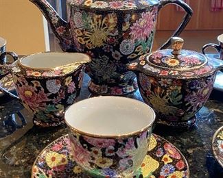 ITEM 68: Black floral tea set with teapot, creamer, sugar and four cups and saucers $70