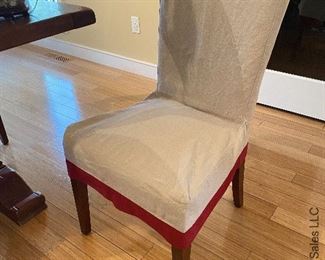 ITEM 139: Set of 8 Pottery Barn parsons chairs. Upholstered in khaki, slipcovered in beige linen with red trim. Some minor wear damage consistent with age $600