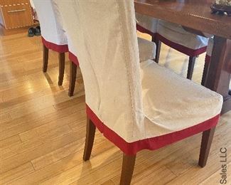 ITEM 139: Set of 8 Pottery Barn parsons chairs. Upholstered in khaki, slipcovered in beige linen with red trim. Some minor wear damage consistent with age $600
