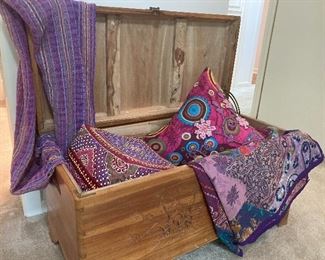 Cedar chest with lilac throws and pillows.
