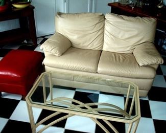 White faux leather settee, red leather ottoman and glass & wrought iron coffee table.
