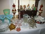 Table of both porcelain and glassware including some Hummels, Alladin oil lamp base, Opal hobnail pieces, porcelain urns and a great curio shelf