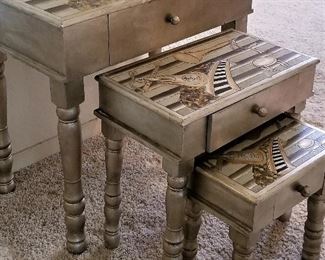 Silver nesting tables. Musical instruments are depicted on the top of each table. 