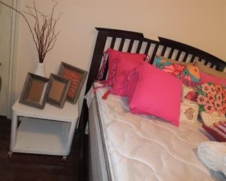Full size bed (guest room) with pretty throw pillows.  Home decor and small rolling table