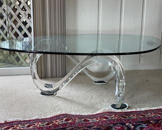 Wave pedestal cocktail table by Interlude. Lucite base with glass top. Measures 50"L x 36"W x 16"H. Photo 1 of 2