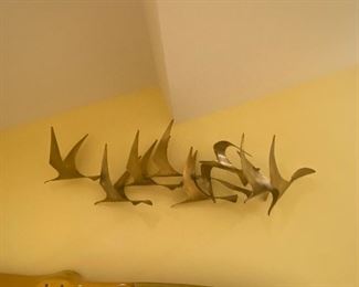  CURTIS JERE BIRDS IN FLIGHT WALL SCULPTURE
(C. Jeré is a metalwork artist of wall sculptures and household accessories.&nbsp; C. Jeré works are made and marketed by the corporation Artisan House. Curtis Jere is a compound nom-de-plume of artists Curtis Freiler and Jerry Fels. The two founders combined pieces of their own names to create the C. Jeré signature.&nbsp;
Modernism&nbsp;magazine interviewed Jerry Fels shortly before his death in October 2008. According to the resulting article in the Spring 2007 issue of&nbsp;Modernism&nbsp;magazine page 116, the company was founded in 1963 by Fels and his brother-in-law Curtis (Kurt) Freiler. Freiler was the production chief and Fels was head of design. Their goal was to produce "gallery-quality art for the masses".&nbsp; Kurt and Jerry sold Artisan House in 1972.&nbsp; Sold and resold, the company still produces metal sculptures including reintroductions of popular mid-century designs. Artisan House sculptures are no longer made in California. Production went overseas to Ch