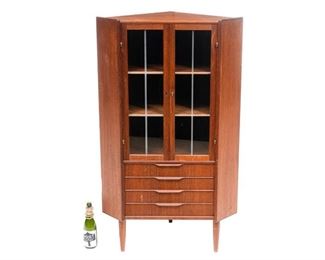 Danish Mid-Century corner cabinet, two glazed doors opens to shelved interior, above four drawers, includes key, rising on pin legs.
57"h x 32"w x 23"d