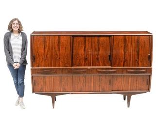 Danish Mid-Century sideboard, arched front, three sliding doors open to mirrored and shelved interior, above four drawers and four sliding doors, rising on pin legs.
51"h x 79"w x 18"d
