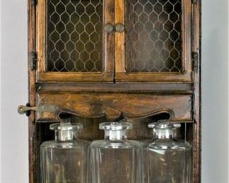 24 Wall Mounted Wooden Cabinet & Decanters Wooden wall mounted cabinet, with 3 crystal decanters. 11 1/2"W x 4 1/2"D x 24"H, each decanter 9 1/4"H. Chip to one bottle, bottom of one stopper damaged.