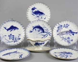 103 Grouping of Fish Porcelain Plates and Sauce Boat Lot includes six gilt plates with different blue fish motifs on each, illegible impressed mark, 9" diameter, some chips and paint wear; gilt and fish motif sauce boat with fixed under plate, 4"T x 81/2"W, some wear to paint from use.