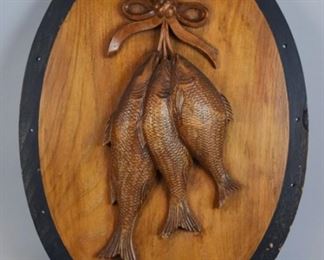 106 Black Forest Carved Fish Plaque Carved wooden plaque depicting three caught fish. 21" x 15 1/2". Chip along one edge