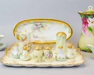 162 German and Austrian Porcelain Tableware Grouping Gilt and floral hand painted porcelain coffee pot, 10"T x 7"W, some minor chips on inside of lid from use; gilt and floral porcelain sugar shaker with Bavaria mark, 4 1/2"T, no chips, two gilt and pink floral salt and pepper shaker sets marked C&Z Austria, 2 1/2"T, some paint wear with use; one gilt and yellow floral salt and pepper shaker set marked Bavaria, 2 1/2"T, some paint wear with use; artist signed gilt and floral hand painted candy dish with Vienna Austria mark, 7"L, no chips; gilt and floral handpainted oval platter with Vienna Austria mark, 13"L x 6"W, no chips; gilt and floral hand painted porcelain creamer marked Germany with underplate, 5 1/2"T, no chips; gilt and floral hand painted porcelain gravy boat marked Bavaria Germany; gilt and floral hand painted porcelain tray, marked with B, 16" x 13", some wear on paint edges, no chips