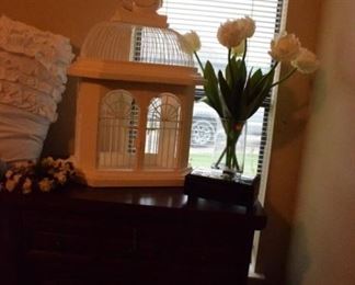 Nightstand that matches dresser. Birdcage and flora.