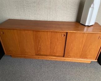 Solid teak mid century credenza with sliding doors and two interior shelves and velvet lined drawers for flatware.