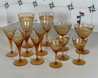 (12pc) AMBER GLASSWARE | Including a set of 5 small glasses [with chips to rim], plus a set of matching glasses with etched/gilt design in three different sizes; tallest h. 7 in. 
