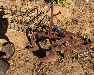 Old, really old plow. Behind it is an unusual horseshoe garden fence border.