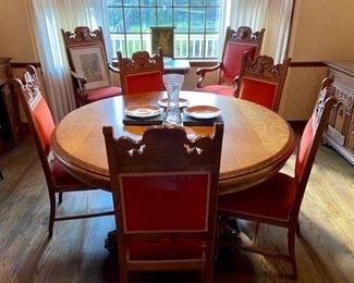 Antique Empire Style Quarter Sawn Oak Pedestal Dining Table features lavish baroque carved claw feet and lions' head on chairs upholstered in a plush orange-red velvet. Exquisite 9-PC set includes: pedestal table, extra leaves, and 8 chairs (6 parlor, 2 arm chairs)