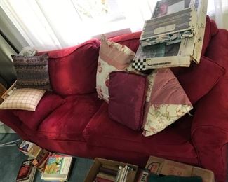 Red napped fabric couch with pull-out bed and pillows