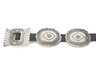 191
A Navajo Concho Belt
Second quarter 20th century
A leather belt with nine (9) silver & turquoise conchos, plus a stone set rectangular buckle
Each concho: 3" L x 2.50" W; Leather length: 34"
387 grams
Estimate: $500 - $700