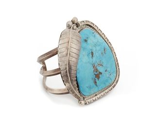 210
A Navajo Turquoise Cuff Bracelet
Mid-20th Century
Marked: M possibly for Mary Morgan (Dine)
A large slab turquoise stone set into a stamped and feather setting with split shank cuff
6.5" L x 3" H x 2.40" W
118 grams
Estimate: $600 - $800