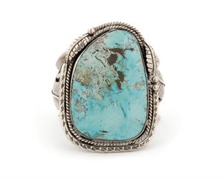 209
A Large Navajo Turquoise Slab Cuff Bracelet
Mid 20th century
Marked to interior: NC / J-AgA-MS-1 5
A large turquoise stone set into a rope and stamped bezel with feather and ball motif and a split shank cuff
Ring size 7 <br /> 7" L x 3.5" H x 2.5" W
234 grams
Estimate: $800 - $1,200