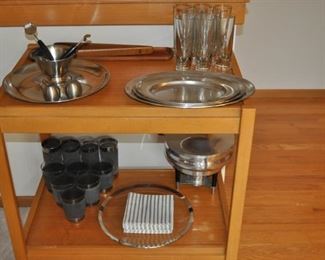 Dolphin MCM Danish Modern folding teak tea cart, MCM barware and tools, MCM chafing dish/buffet server Spain, Stelton MCM Denmark stainless steel round tray w/bowl, Dansk wooden tongs, Gump’s “Bullit” MCM glass barware Italy, Cultura stainless MCM oval trays AB Silver & Stal Sweden 
