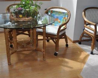 PTMC rattan round glass topped table 48” diameter w/4 arm chairs w/wheels and upholstered seats, house plants