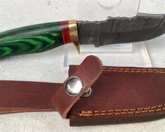 Mfg - Custom Hand Made Damascus
Model - Steel Knife 4.25" Blade
This lot contains a Custom hand made Damascus steel knife. This knife has a 4.25" blade with an emerald green and red stained wooden handle with brass guard and pommel, overall length of 8". Comes with a custom leather embossed sheath.