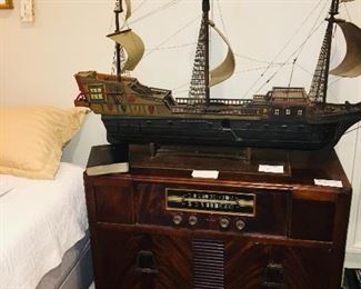 fine old ship model sitting on top of an early console radio