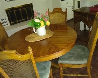 Beautiful grained wood dining table with chairs. Four chairs on the property and leaves for expansion.