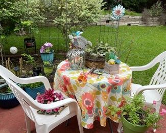 Glass top table with table cloth, plastic chairs, yard art