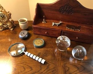 Wooden wall mounted curio shelf with two drawers, ornate desk clock magnifier, solid glass Apple and paperweights