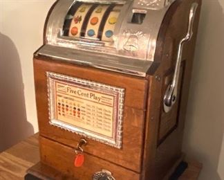 Jennings Operators Bell Five Cent Slot Machine for hours of home entertainment. Comes with they and is in working order. Features quartersawn oak case with gooseneck coin receiver. 

Measures 15" w x 26" h x 14" d 